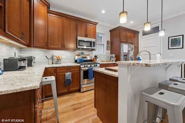 2531 W Lyndale St, Chicago, IL 60647 - kitchen featuring stainless steel appliances, crown molding, a kitchen breakfast bar, decorative backsplash, and light wood-style flooring
