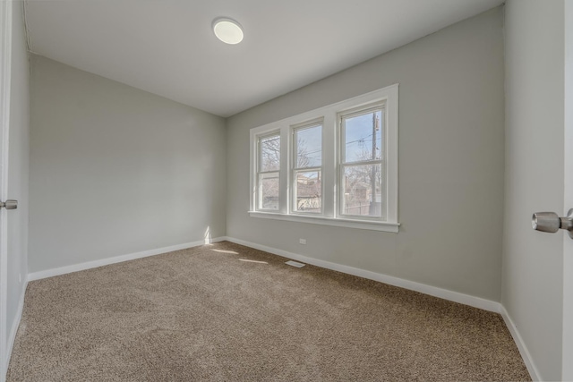 carpeted spare room with visible vents and baseboards