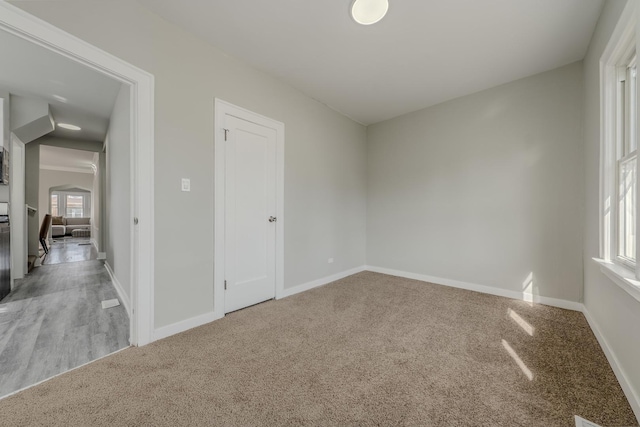 empty room featuring light carpet and baseboards