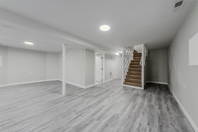 finished basement featuring baseboards, stairs, visible vents, and wood finished floors