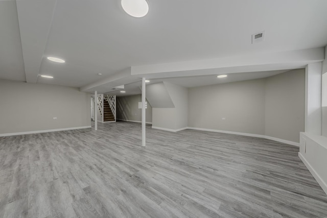 finished basement with stairs, wood finished floors, visible vents, and baseboards