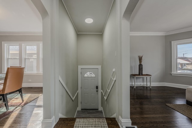 foyer entrance featuring arched walkways, ornamental molding, dark wood finished floors, and baseboards