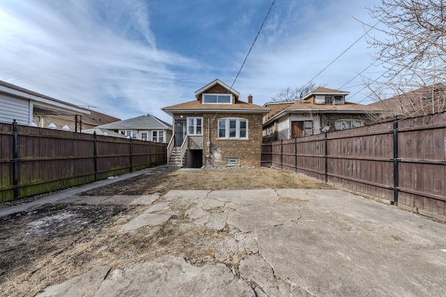 back of house featuring a fenced backyard and brick siding