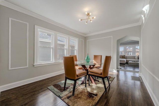 dining room featuring baseboards, arched walkways, dark wood-style floors, an inviting chandelier, and crown molding