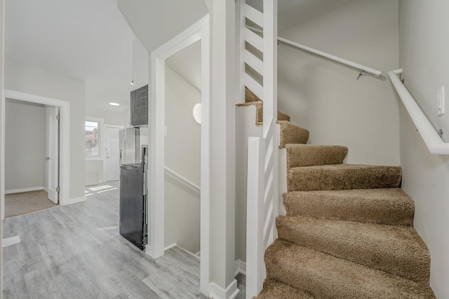 staircase featuring baseboards and wood finished floors