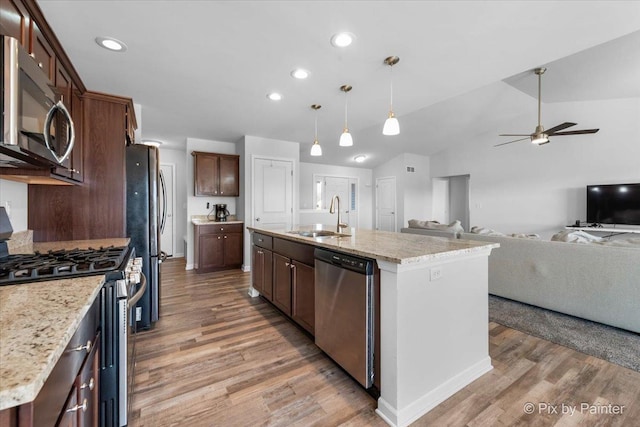 kitchen with stainless steel appliances, open floor plan, a sink, and light wood finished floors