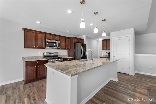 kitchen with dark wood-style floors, a kitchen island with sink, stainless steel appliances, and a sink