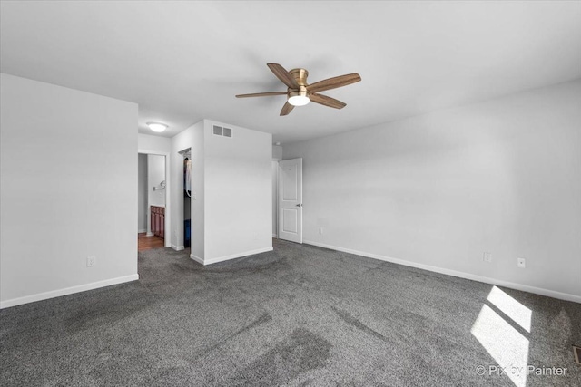 spare room featuring dark colored carpet, a ceiling fan, visible vents, and baseboards