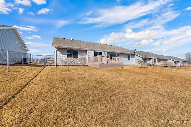 rear view of property with a gate, a yard, a deck, and fence