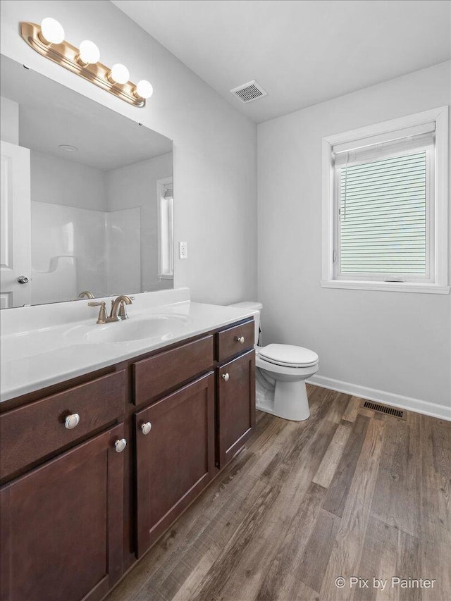 bathroom featuring toilet, visible vents, wood finished floors, and vanity