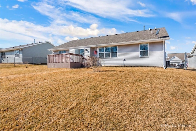 rear view of property with a wooden deck, fence, and a yard