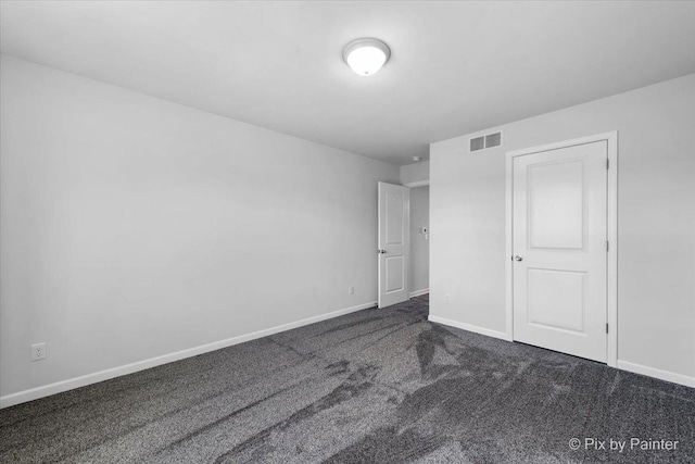 unfurnished bedroom featuring visible vents, dark carpet, and baseboards