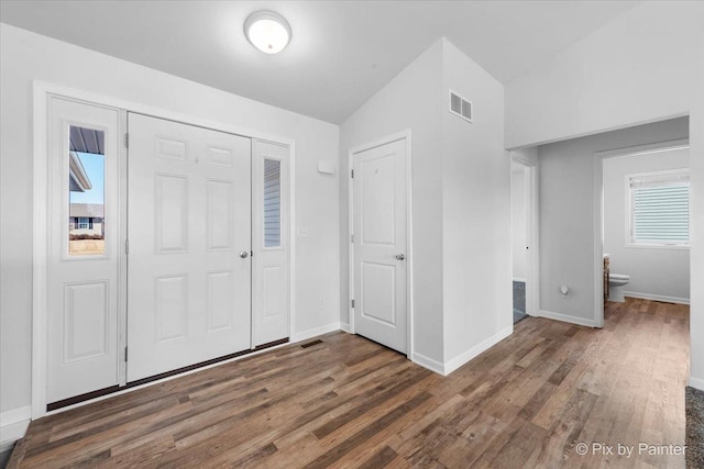 unfurnished bedroom with vaulted ceiling, wood finished floors, visible vents, and baseboards