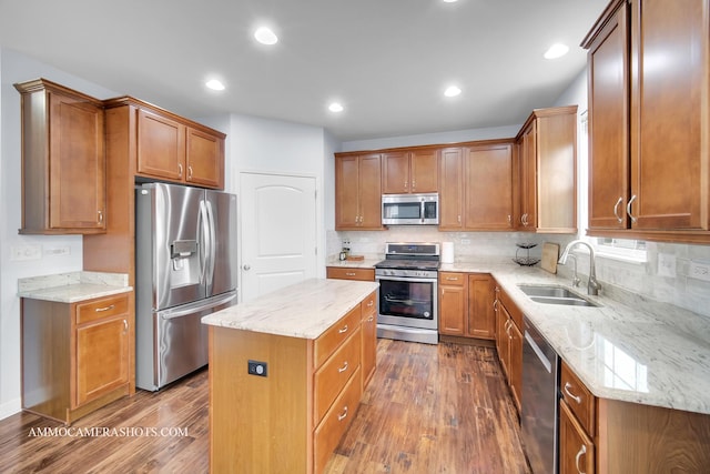 kitchen with stainless steel appliances, dark wood-type flooring, a sink, and a center island