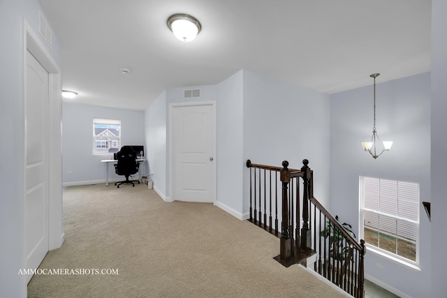 hallway with a notable chandelier, visible vents, carpet flooring, an upstairs landing, and baseboards