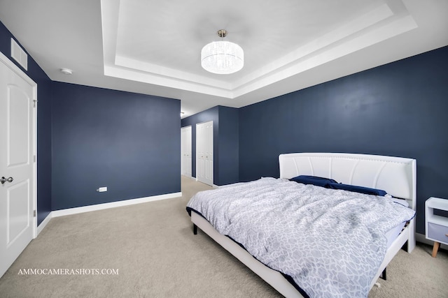 bedroom with a notable chandelier, carpet floors, a tray ceiling, and baseboards