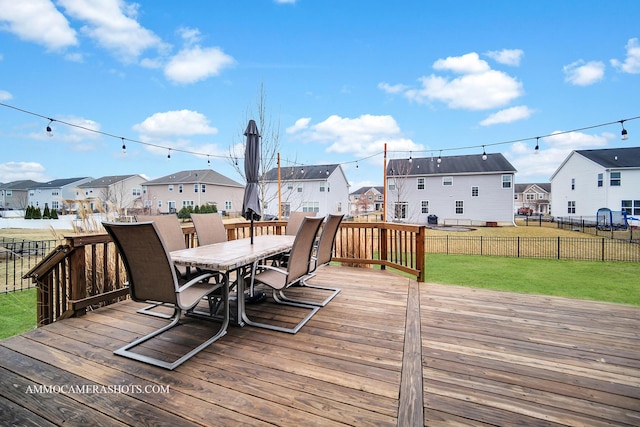 wooden terrace with a residential view, outdoor dining area, and a lawn