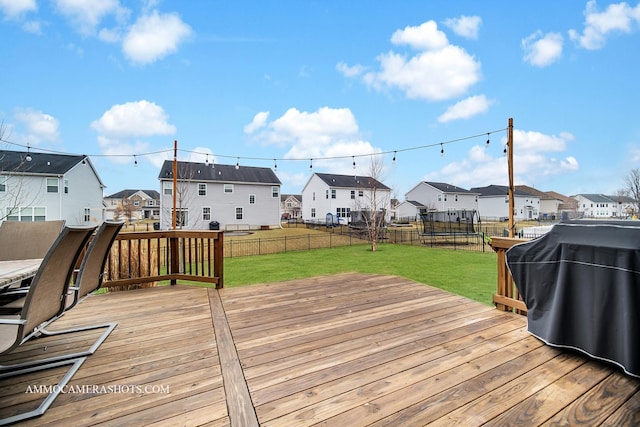 deck with a lawn, a trampoline, and a residential view