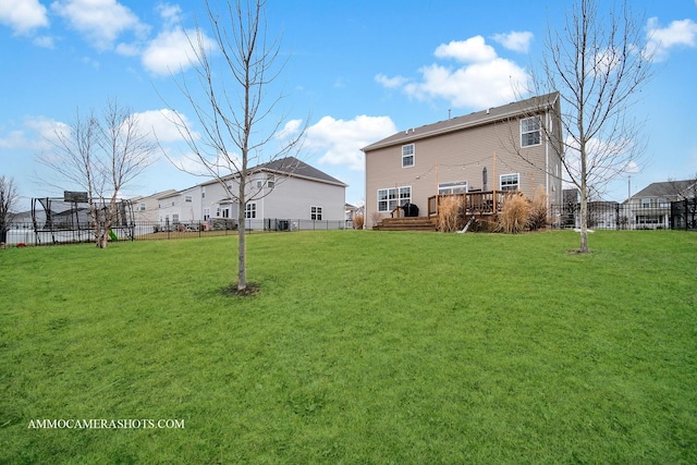 back of property with fence, a deck, and a yard