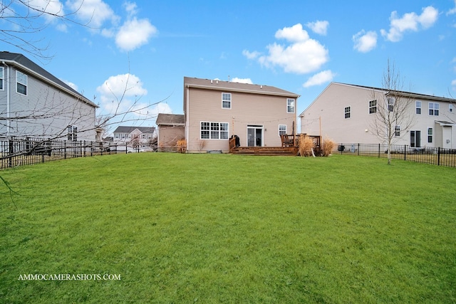 rear view of house with a fenced backyard, a deck, and a lawn