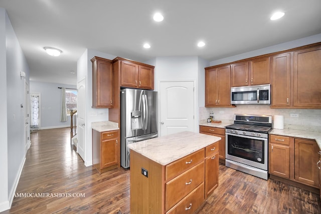 kitchen featuring stainless steel appliances, a kitchen island, light stone countertops, dark wood-style floors, and tasteful backsplash