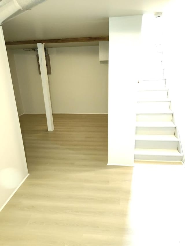 finished basement featuring light wood finished floors and stairway