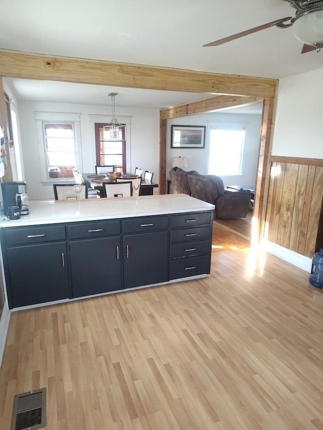 kitchen featuring light wood finished floors, visible vents, wainscoting, ceiling fan, and light countertops