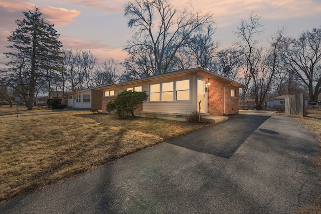 view of front of house with crawl space, a yard, aphalt driveway, and brick siding