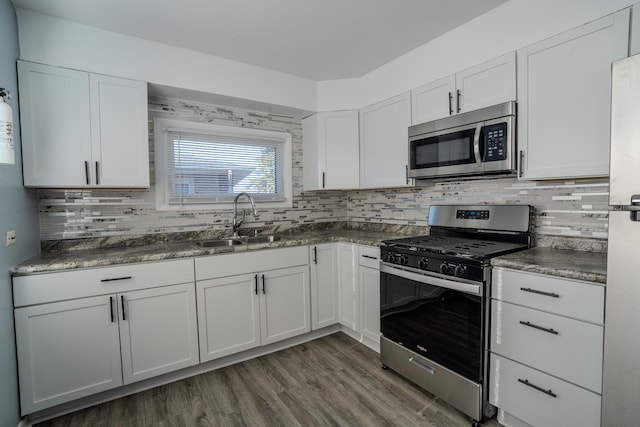 kitchen with stainless steel appliances, dark countertops, and a sink