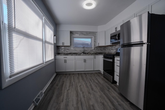 kitchen with dark wood-style flooring, visible vents, appliances with stainless steel finishes, white cabinets, and a sink