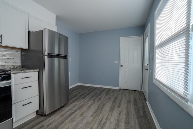 kitchen with dark wood-type flooring, freestanding refrigerator, white cabinets, range, and baseboards