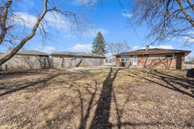 back of property featuring brick siding, fence, and a chimney