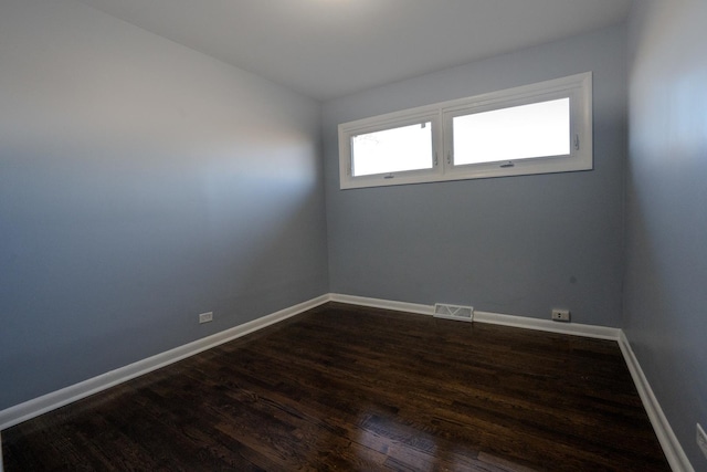 spare room with visible vents, baseboards, and dark wood-type flooring