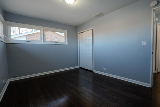 interior space with dark wood-style flooring, a closet, visible vents, and baseboards