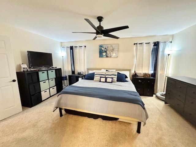 bedroom with a ceiling fan and light colored carpet