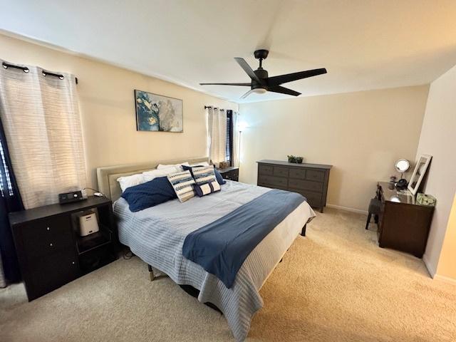 bedroom featuring light carpet, ceiling fan, and baseboards