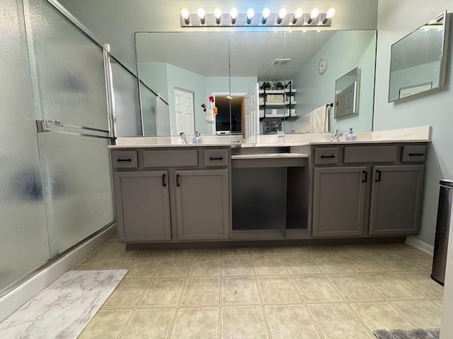 bathroom featuring double vanity, a stall shower, and a sink