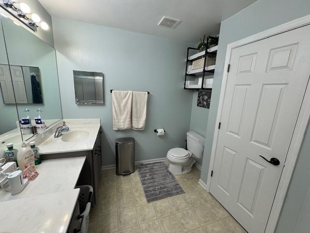 bathroom with toilet, baseboards, visible vents, and vanity