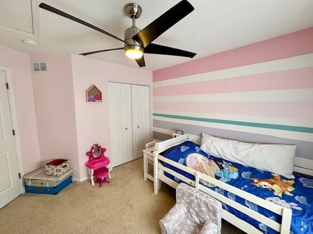 carpeted bedroom featuring a ceiling fan, a closet, and visible vents