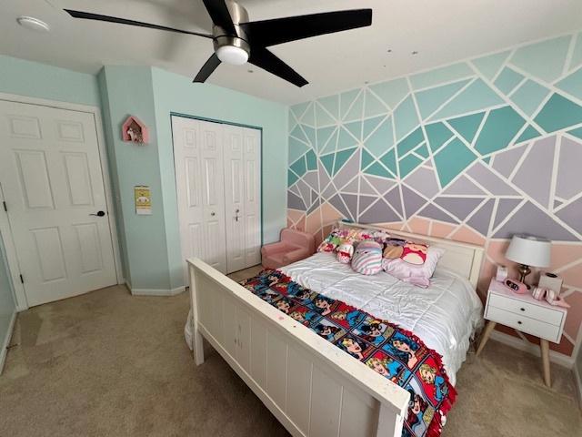 carpeted bedroom with ceiling fan, a closet, and baseboards