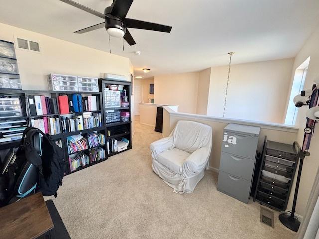 sitting room featuring a ceiling fan, visible vents, and carpet flooring