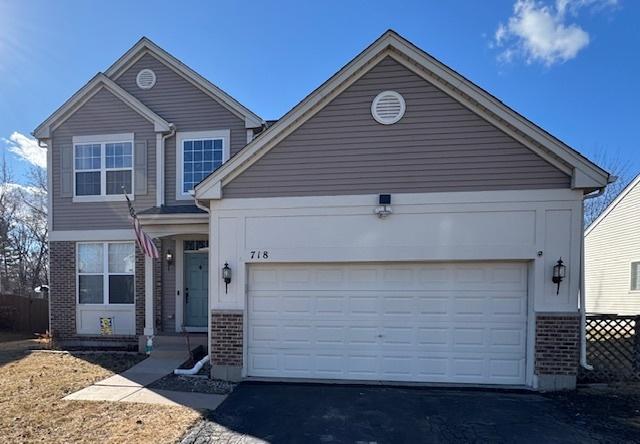 traditional home featuring an attached garage, aphalt driveway, and brick siding