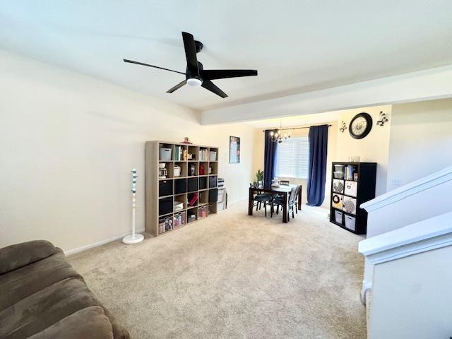 sitting room featuring carpet flooring and ceiling fan with notable chandelier