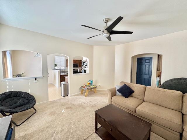 carpeted living room with arched walkways and a ceiling fan