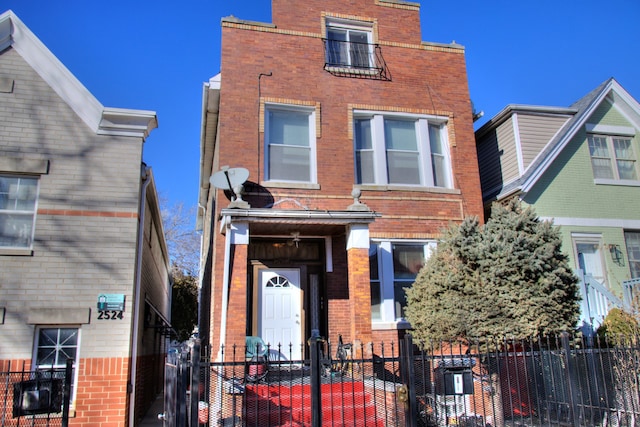 townhome / multi-family property with a fenced front yard and brick siding