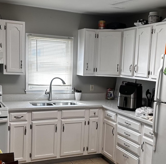 kitchen with light countertops, white appliances, a sink, and white cabinetry