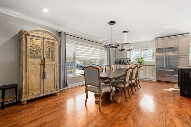 dining room with light wood finished floors, a healthy amount of sunlight, a chandelier, and crown molding