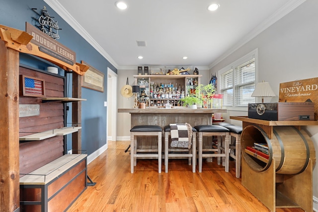 bar featuring baseboards, ornamental molding, wood finished floors, a bar, and recessed lighting