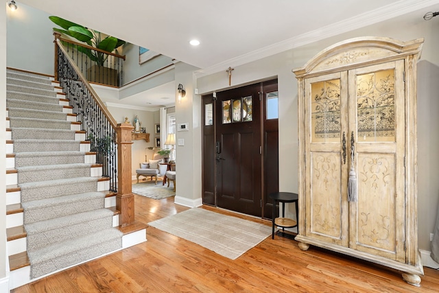 entryway featuring baseboards, stairs, crown molding, light wood-style floors, and recessed lighting