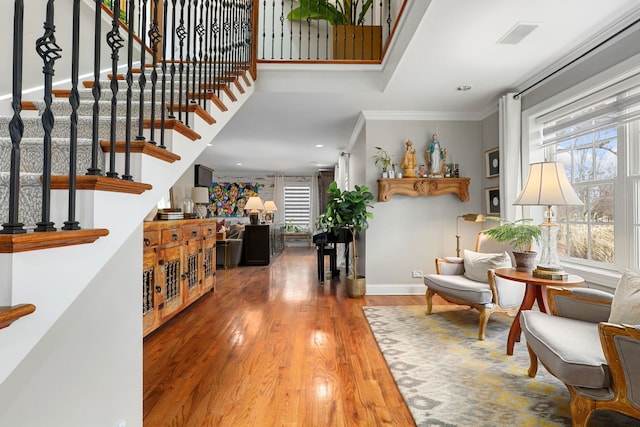 entryway featuring wood finished floors, a towering ceiling, baseboards, stairs, and ornamental molding